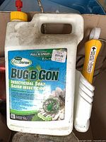 Scotts EcoSense Bug B Gon jug beside white tool handle