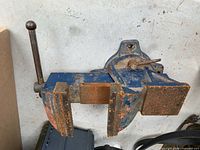 Full view of blue swivel bench vise showing jaws, handle, and anvil area