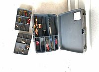 Open Plano tackle box with removable trays and assorted lures, bobber, hooks visible