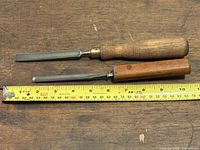 Two chisels laid alongside measuring tape showing lengths
