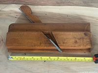 Full view of wooden molding plane with tape measure showing length