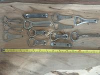 All fourteen vintage openers laid out with measuring tape for scale