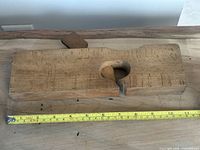 Top view of wooden molding plane body missing blade with tape measure for scale