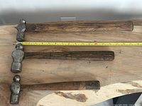 Three hammers laid horizontally with measuring tape