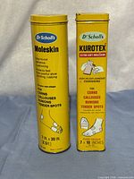 Front view of both Dr. Scholl's moleskin tins showing branding and product information