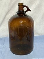 Front view of amber Javex jug showing handle and embossed lettering