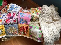 Both throws draped over bed: white knit afghan and floral patchwork quilt