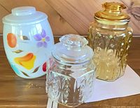 Group shot of three cookie jars: milk glass painted, clear pressed, amber pressed