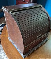 Closed roll-top wooden sewing box on table