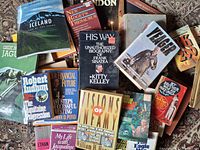 Assorted stack of books showing biographies, finance, fiction, military and travel titles