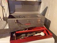 Open Craftsman toolbox on washer, red tray with hand tools and hand saw in foreground