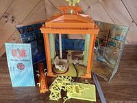 Overall view of playset with roof, walls, chair, door panel, yellow frames and orange beam