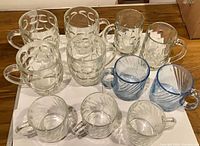 Ten assorted glass mugs arranged on white background