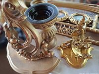 group of gold candle holder, shelf bracket and small framed pieces