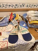 Overview of folded linens, pot holders, towels, packaged goose rug