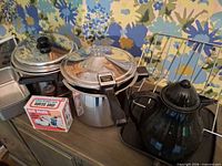 Group shot showing pressure cooker, Dutch oven, coffee pot, diet scale box, hourglass timer, loaf pan, toast rack