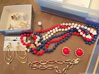 Overview showing several jewelry pieces, Claire’s earrings card, bead necklace, red cabochon earrings, gold chain bracelet