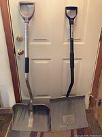 Both shovels leaning against a door