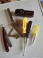 Group shot: multi-tool, sheath, razor, pocket knife, three screwdrivers