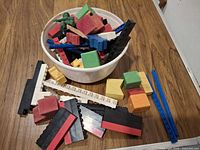 Overview of bowl containing mixed Lego pieces, painted wooden blocks and green army figure