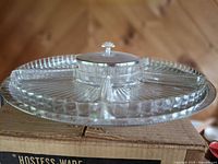 Clear glass divided relish tray with central lidded bowl on rotating base atop box