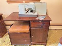 Cabinet with sewing machine on top, stool below, shows overall furniture and machine