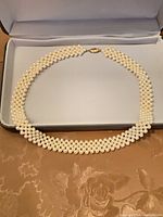 Full view of woven cream bead necklace in presentation box