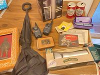Group shot showing massager, air cooler, walkie-talkies, cola cans, umbrella, knight plaque, wallet, 110 camera, packaging