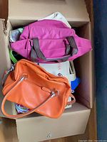 Top view showing magenta bag, orange satchel, other bags in box