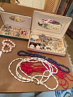 Overview of two open travel jewelry boxes with jewelry pieces displayed