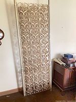 Full view of one scrollwork tension panel leaning against wall