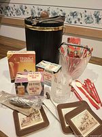 Group shot showing insulated ice bucket, two glass buckets, bottle openers, coasters, cocktail mix boxes, swizzle sticks