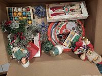 Overview of lot inside box showing bulbs, candles, glass trees, platters, ornaments and décor pieces