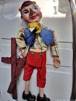 Front view of Pinocchio marionette showing clothing, strings, control bar