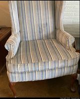 Front view of striped upholstered wing chair showing seat cushion, rolled arms, cabriole legs