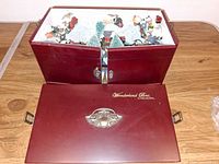 Closed maroon wood box with lid removed showing interior village pieces