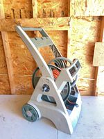 Side view of beige plastic Ames wheeled hose reel cart with green reel and wheels