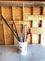 Bucket containing assorted poles, stakes and hooks