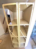 Overall view of two identical beige metal shelving units side by side