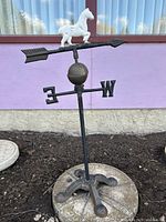 Full view of free-standing cast iron weathervane with horse, arrow, orb, directions and base