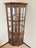 Full front view of corner curio cabinet showing cherry finish and glass doors