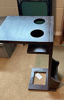Side perspective showing tabletop with two cup holder cut-outs, under-shelf, magazine rack, finish wear