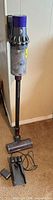 Full view of Dyson V10 stick vacuum with motorhead, dock, and cord
