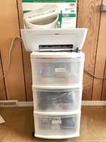 HP DeskJet printer on top of plastic 3-drawer unit with boxed shredder behind