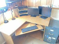 Overall view of L-shaped desk, chair, monitors, keyboard, filing cabinet