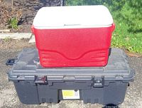 Red cooler stacked on black Plano storage chest