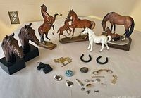Full lot overview showing figurines, horseshoes and jewellery spread on table