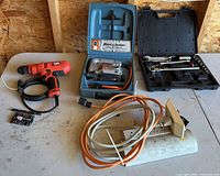 Group shot of drill, jigsaw kit, socket set, extension cords, bits