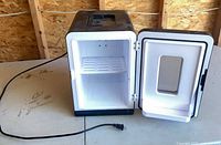 Fridge open showing interior shelf and cord