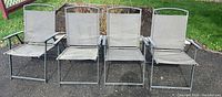Front view of four gray metal folding patio chairs lined up